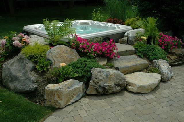 There are ways to set a spa above ground and it will still appear recessed. For this project, we created a secluded area for the hot tub at the edge of a patio and artfully placed boulders, soil and plants to create a “spa set in a garden” effect. It offers the feel of being in-ground without actually being so. (See a “before” photo below.)