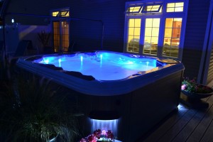 Caption: Exterior LED sconce lights around the outside of a spa perimeter, like this Best Hot Tubs clients’, enhance the nighttime allure of your backyard and help create a safe, illuminated spa environment that will tempt you to a pre-nighty-night soak.