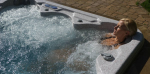 Relaxed woman leaning against jet massage seat with bubbling water all around her;  spa has a metallic.colored inside